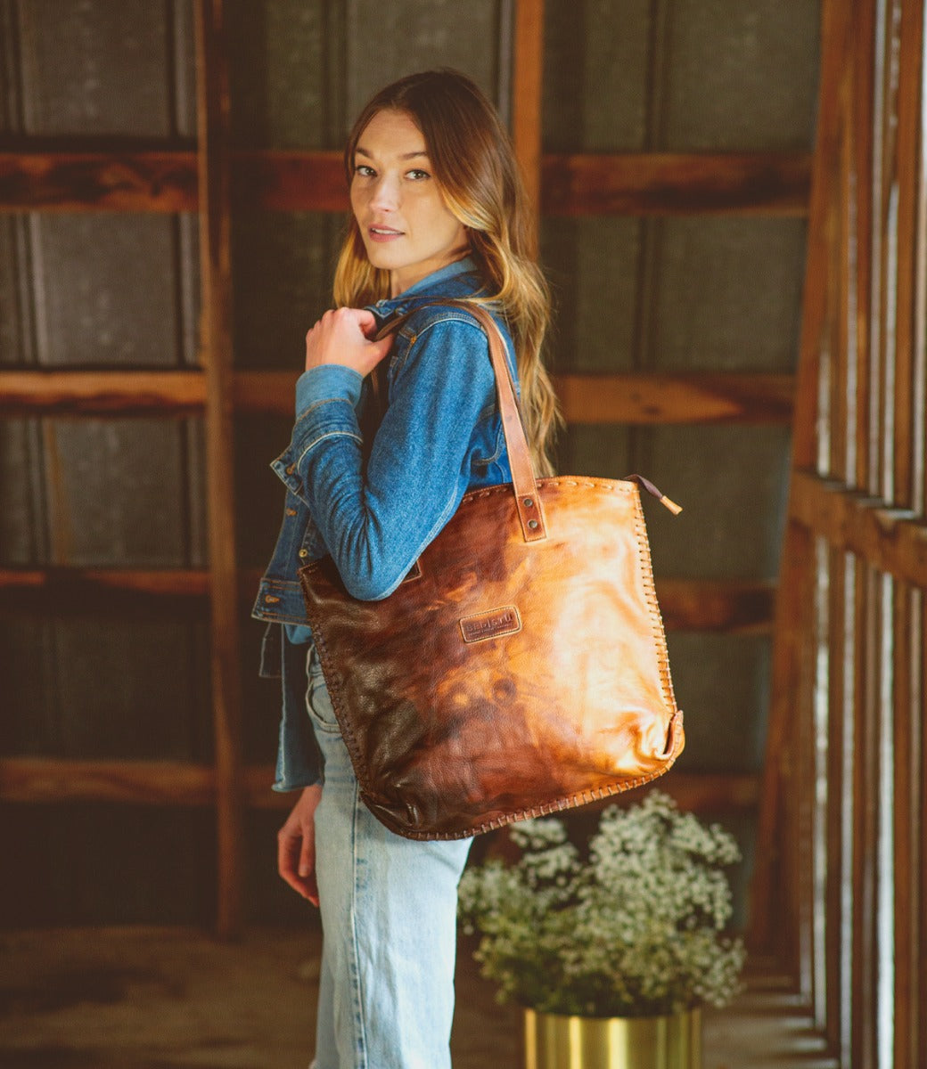 A woman wearing jeans and a Bed Stu Skye II leather tote bag.