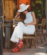 A woman in a white Sloane hat sitting on a wooden bench. (Brand: Bed Stu)