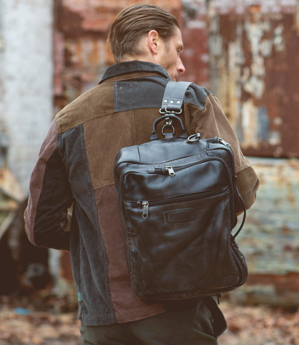 A man carrying a black leather Bed Stu Socrates backpack.