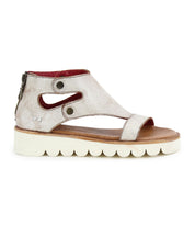 The Bed Stu Soni II is a silver platform sandal featuring a cut-out design, white scalloped XL EXTRALIGHT® outsole for comfort and style, and a back zipper closure.