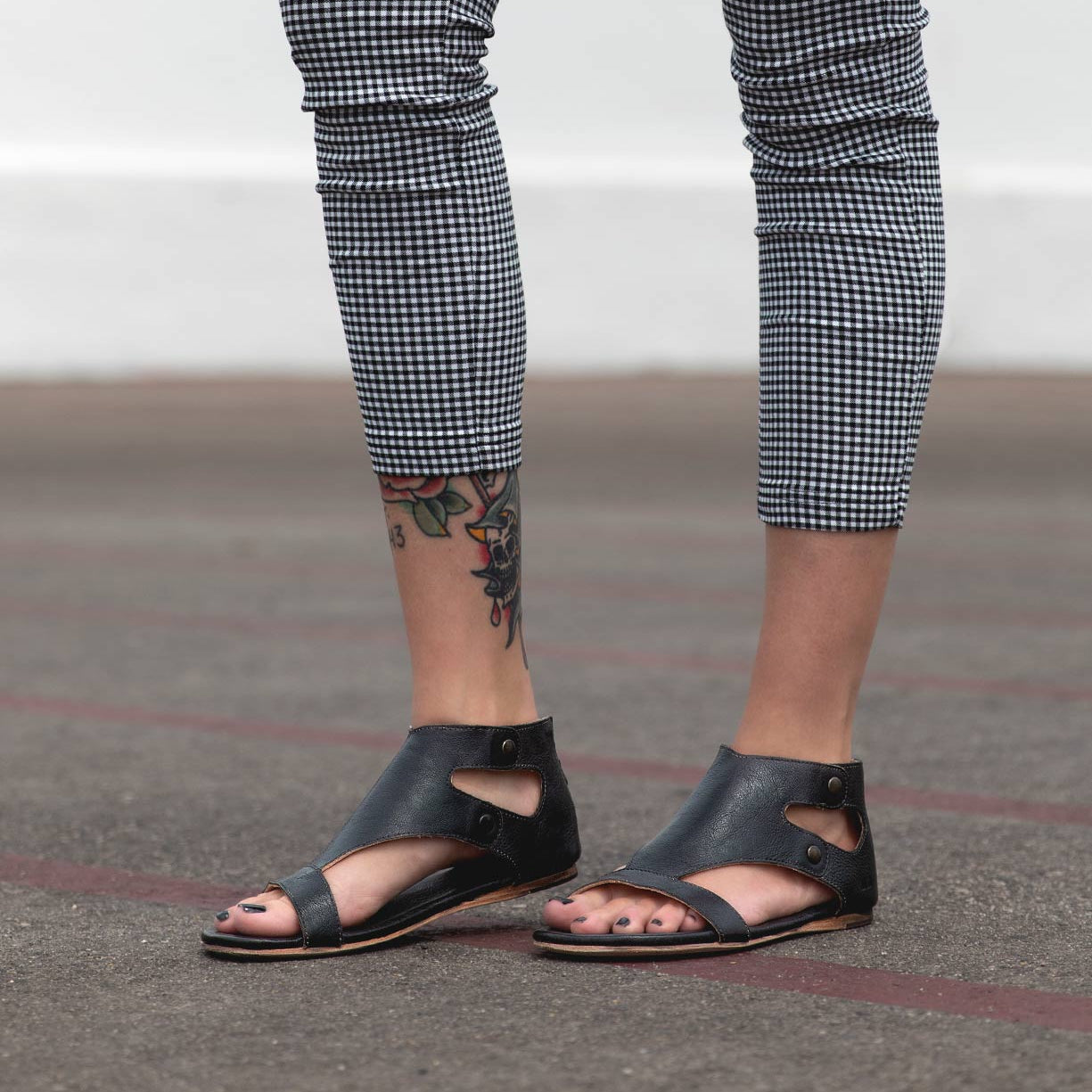 A woman wearing Bed Stu Soto leather sandals and plaid pants.