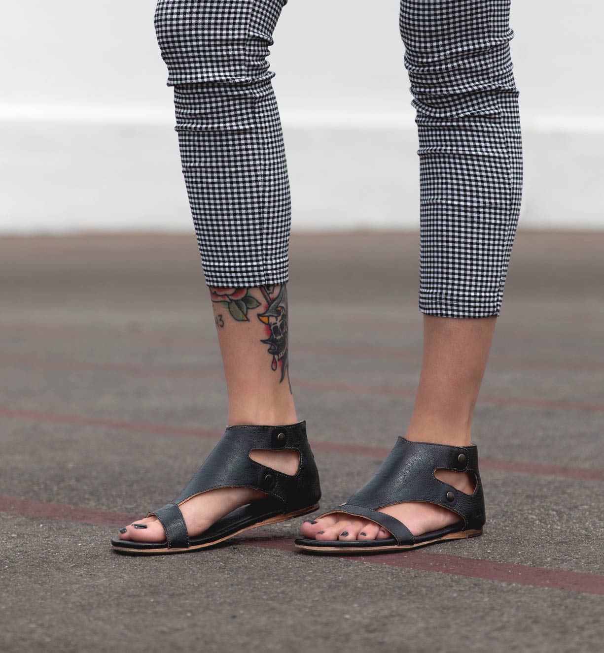 A woman wearing Bed Stu Soto leather sandals and plaid pants.