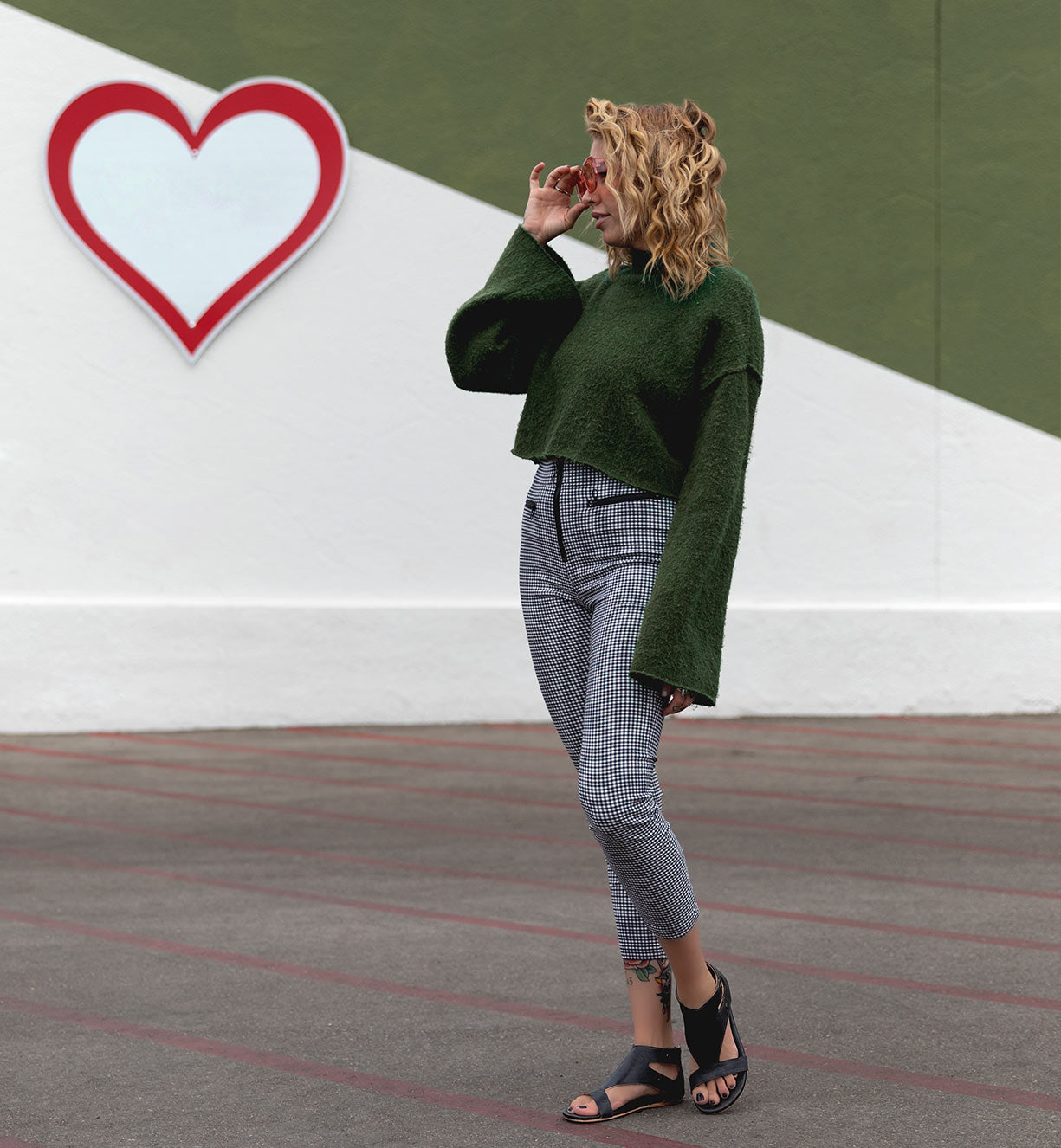 A woman standing in front of a wall wearing Soto leather sandals by Bed Stu.