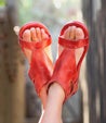 A woman's feet in a pair of Bed Stu red leather sandals (Soto).