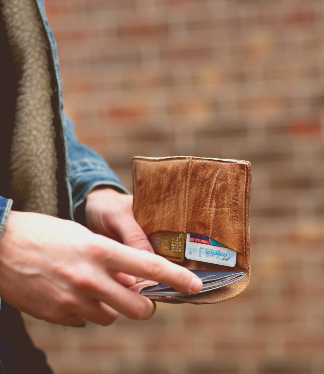 A man holding a Stardust wallet with a credit card in it from the brand Bed Stu.