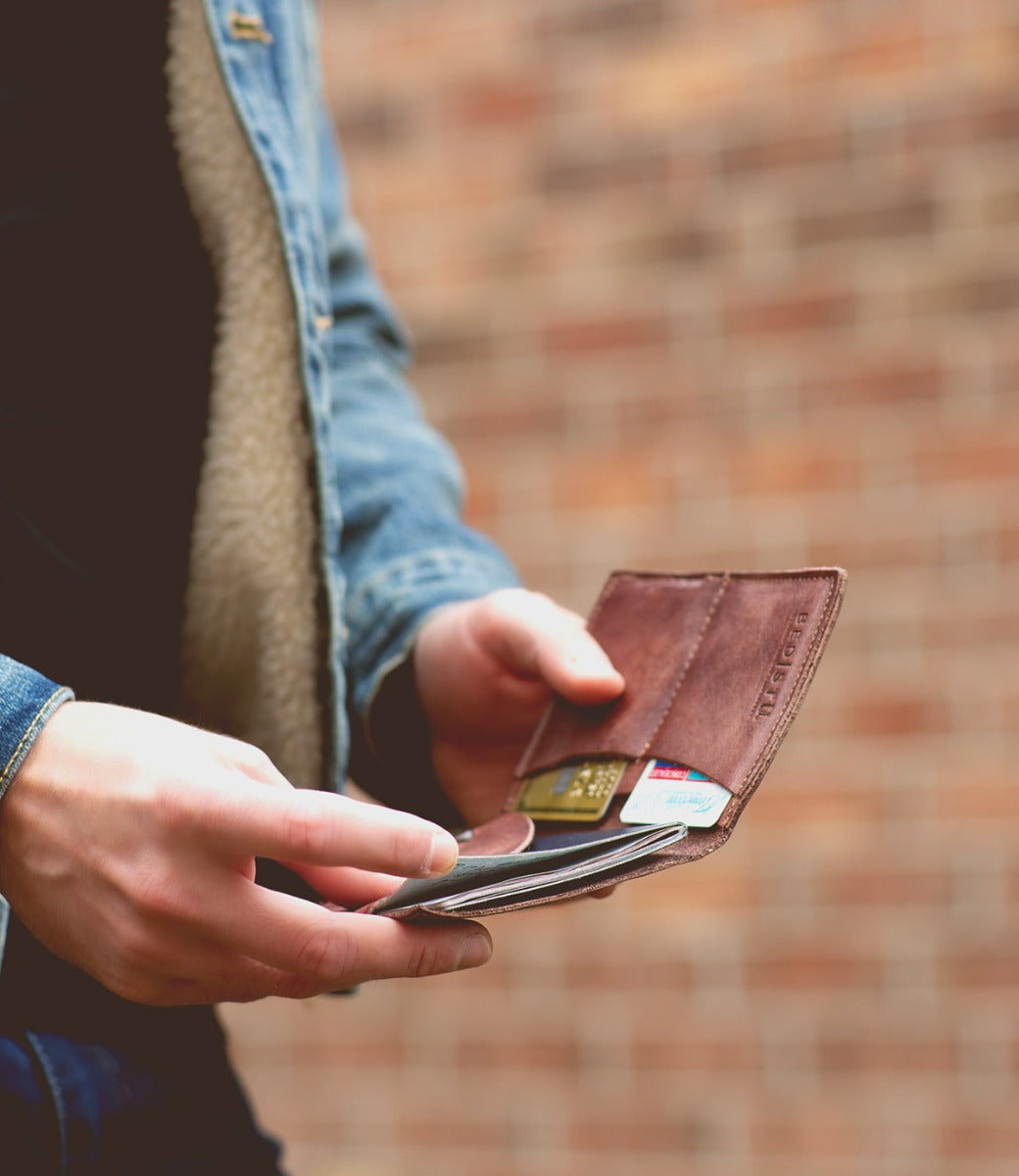 A man holding a Stardust wallet and a Bed Stu cell phone.