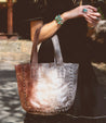 A woman is holding a brown leather Bed Stu Stevie tote bag.