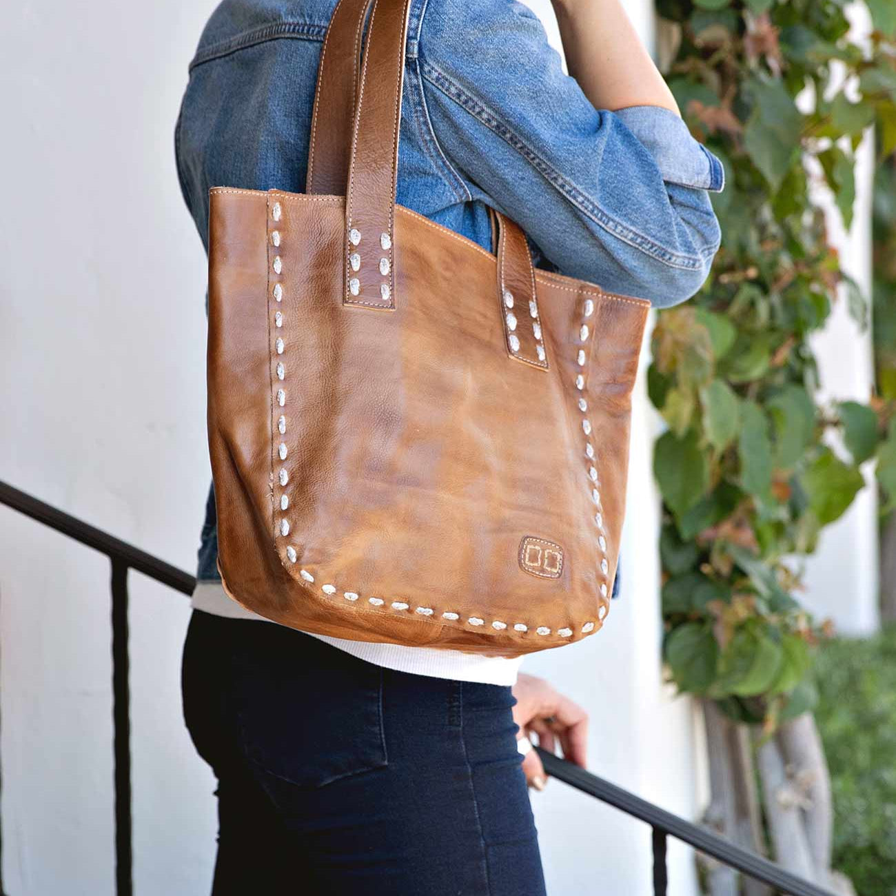 A woman holding a Stevie leather tote bag by Bed Stu.