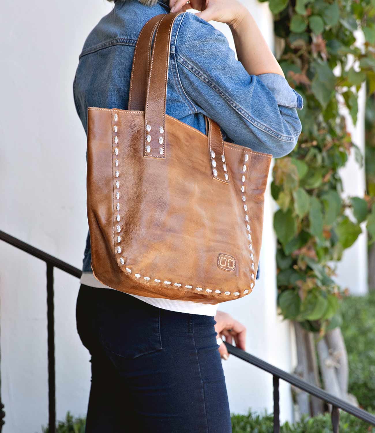 A woman holding a Stevie leather tote bag by Bed Stu.