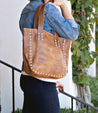 A woman holding a Stevie leather tote bag by Bed Stu.
