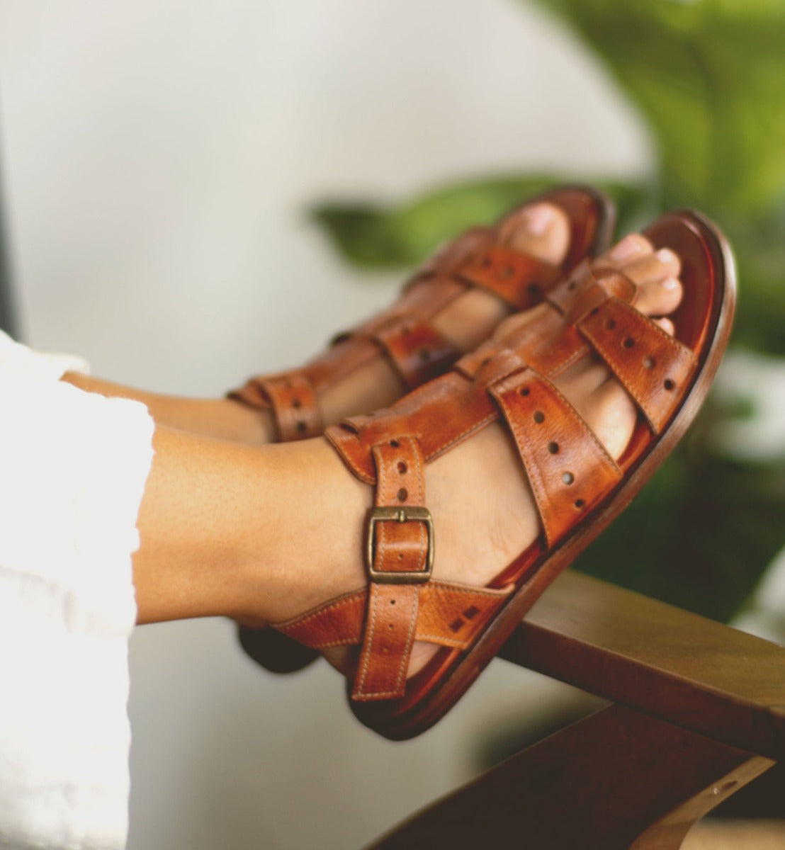 A woman's feet in a pair of Bed Stu brown sandals named Sue.