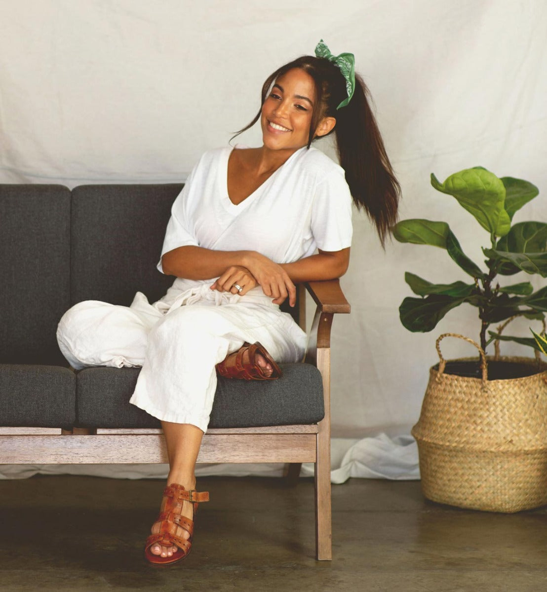 A woman sitting on a couch next to a Bed Stu potted plant named Sue.