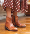 A woman wearing a Tabitha polka dot dress and Bed Stu brown leather ankle boots.