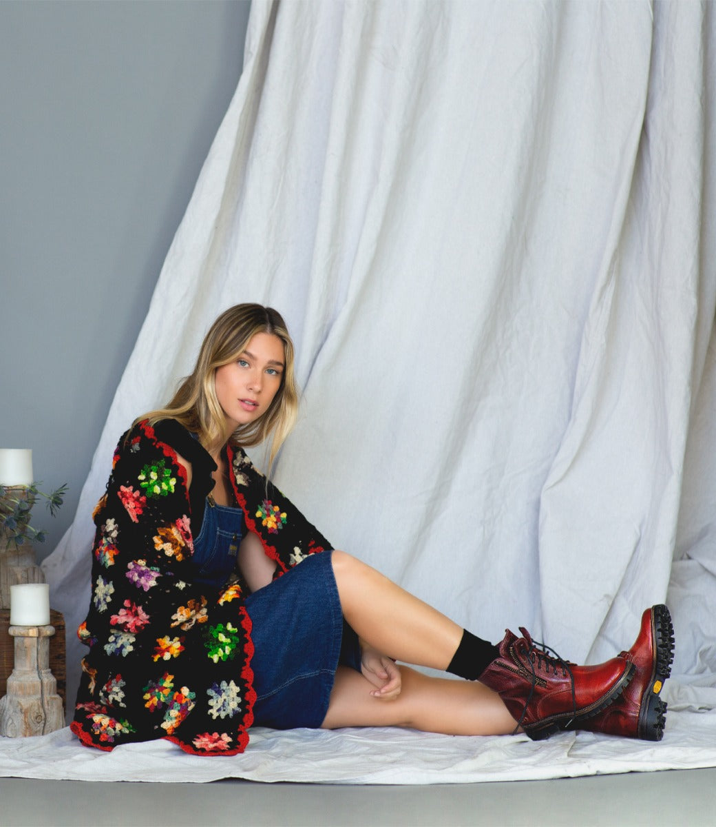 A woman is sitting on a blanket with Bed Stu embroidered boots.