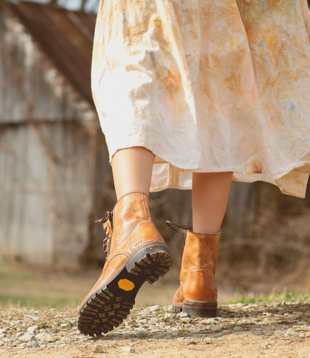 A woman in a Tactic Trek dress and Bed Stu boots walking down a dirt road.
