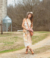 A woman in a Bed Stu cowboy hat and Bed Stu cowboy boots standing in front of a silo.