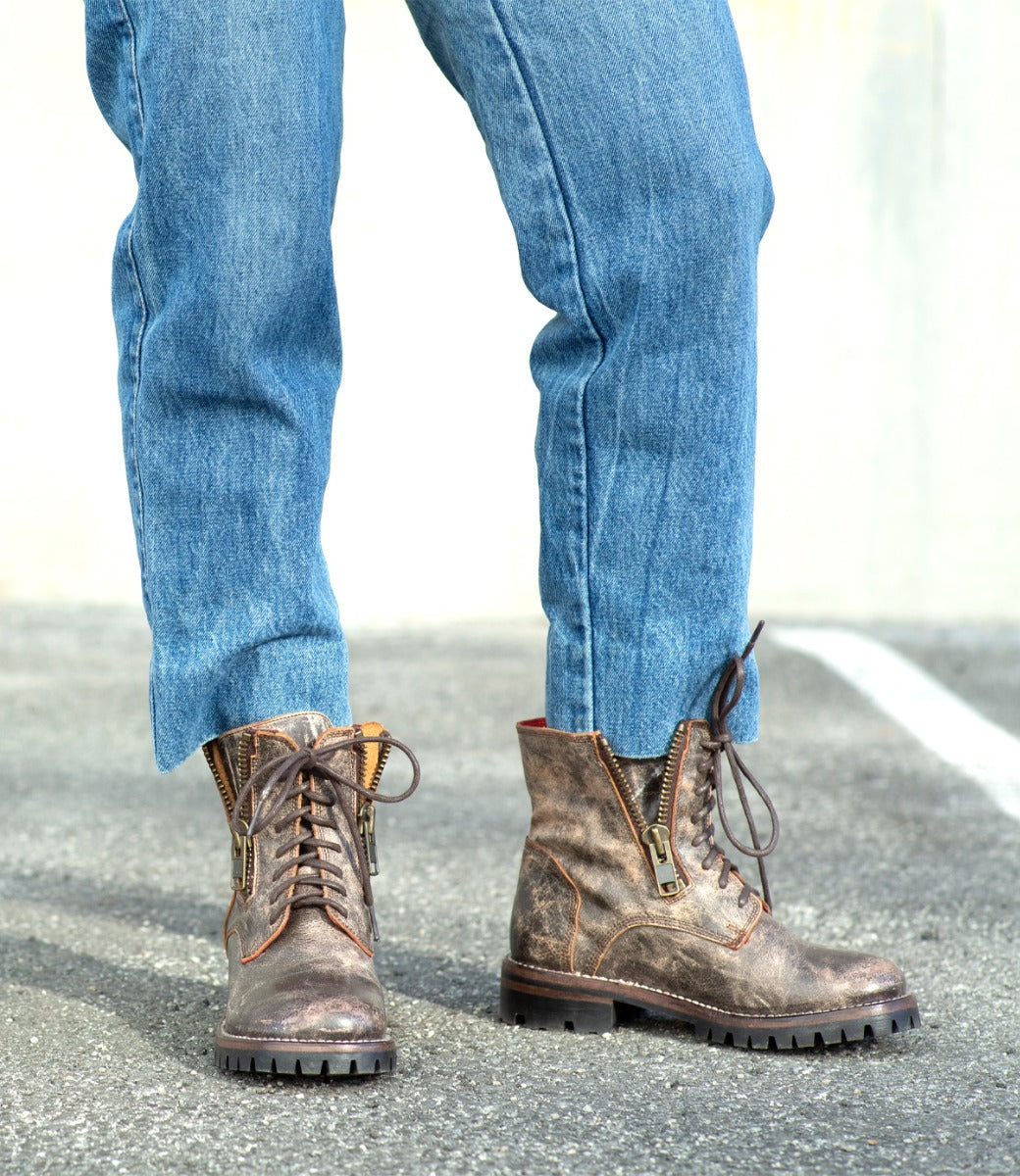 A person in Tactic Trek jeans and Bed Stu boots standing in a parking lot.