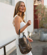 A woman in a white dress holding a Bed Stu Tahiti purse.