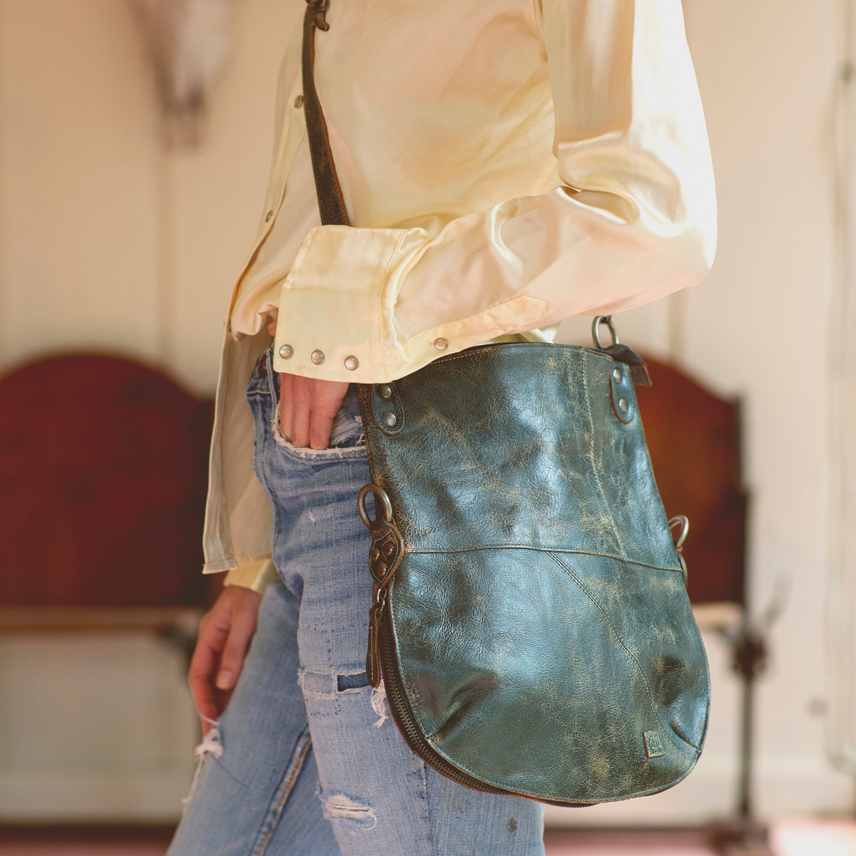 A woman wearing jeans and a green leather Bed Stu Tahiti bag.