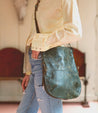 A woman wearing jeans and a green leather Bed Stu Tahiti bag.