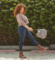 A woman wearing jeans and a brown Bed Stu Tahiti purse.