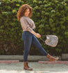 A woman wearing jeans and a brown Bed Stu Tahiti purse.