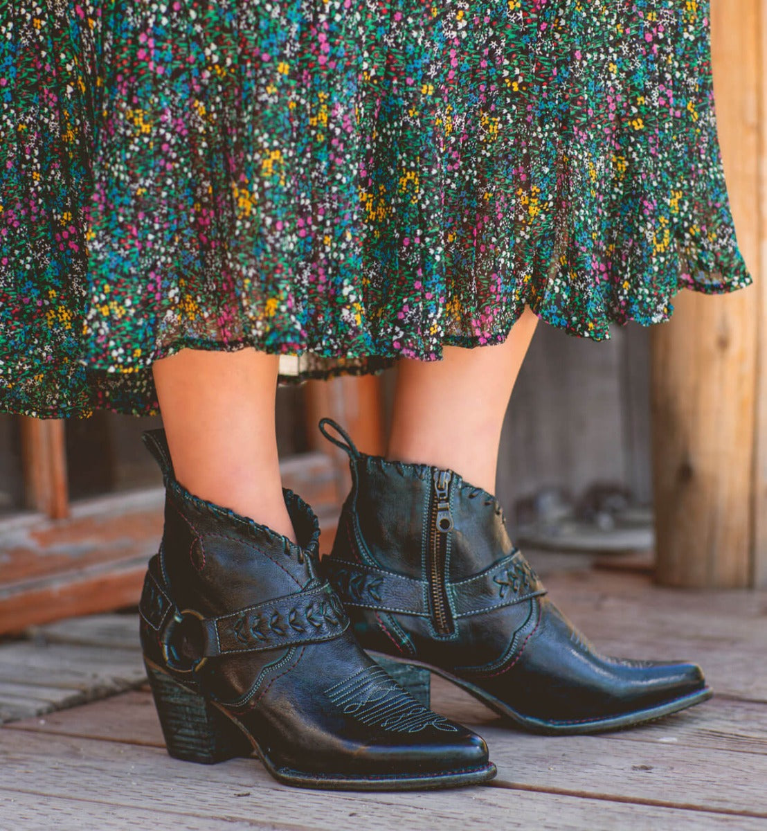 A woman wearing black Bed Stu cowboy boots and a floral skirt named Tania.