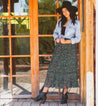 A woman wearing a Tania hat and skirt in front of a wooden door. (Bed Stu)