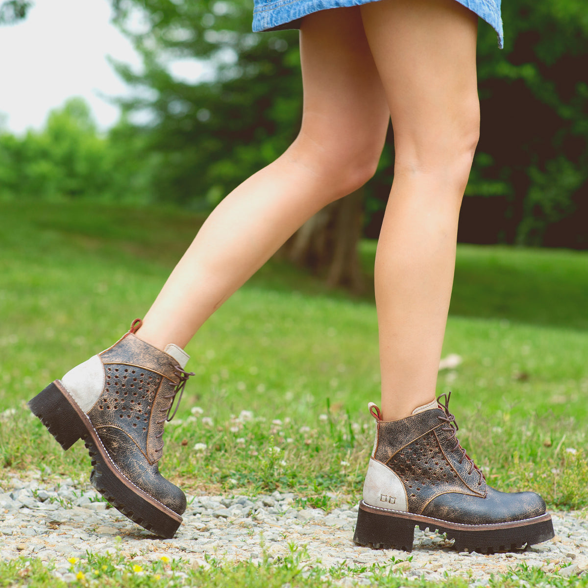 A woman is walking on a dirt road in a pair of Bed Stu Tanzania boots.