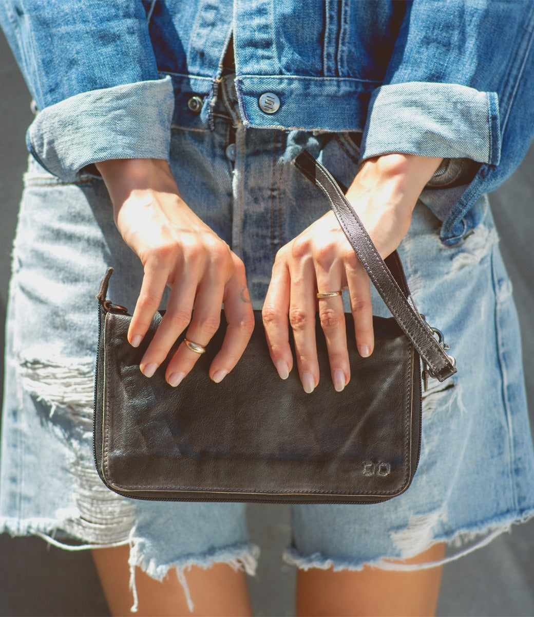 A woman holding a Bed Stu Templeton II black leather clutch.