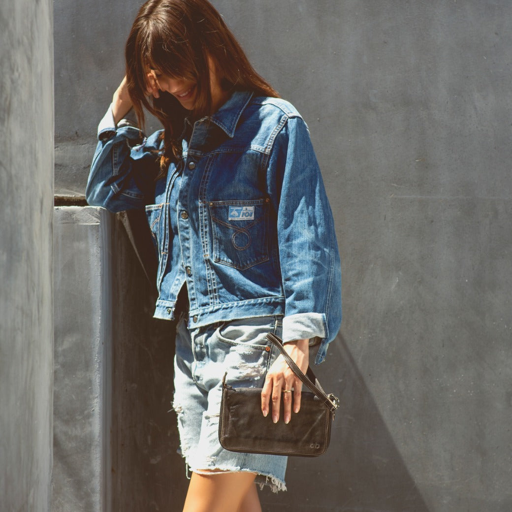 A woman holding a Bed Stu Templeton II black pure leather clutch.