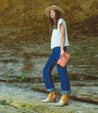 A woman holding a Bed Stu Templeton II pink pure leather clutch.