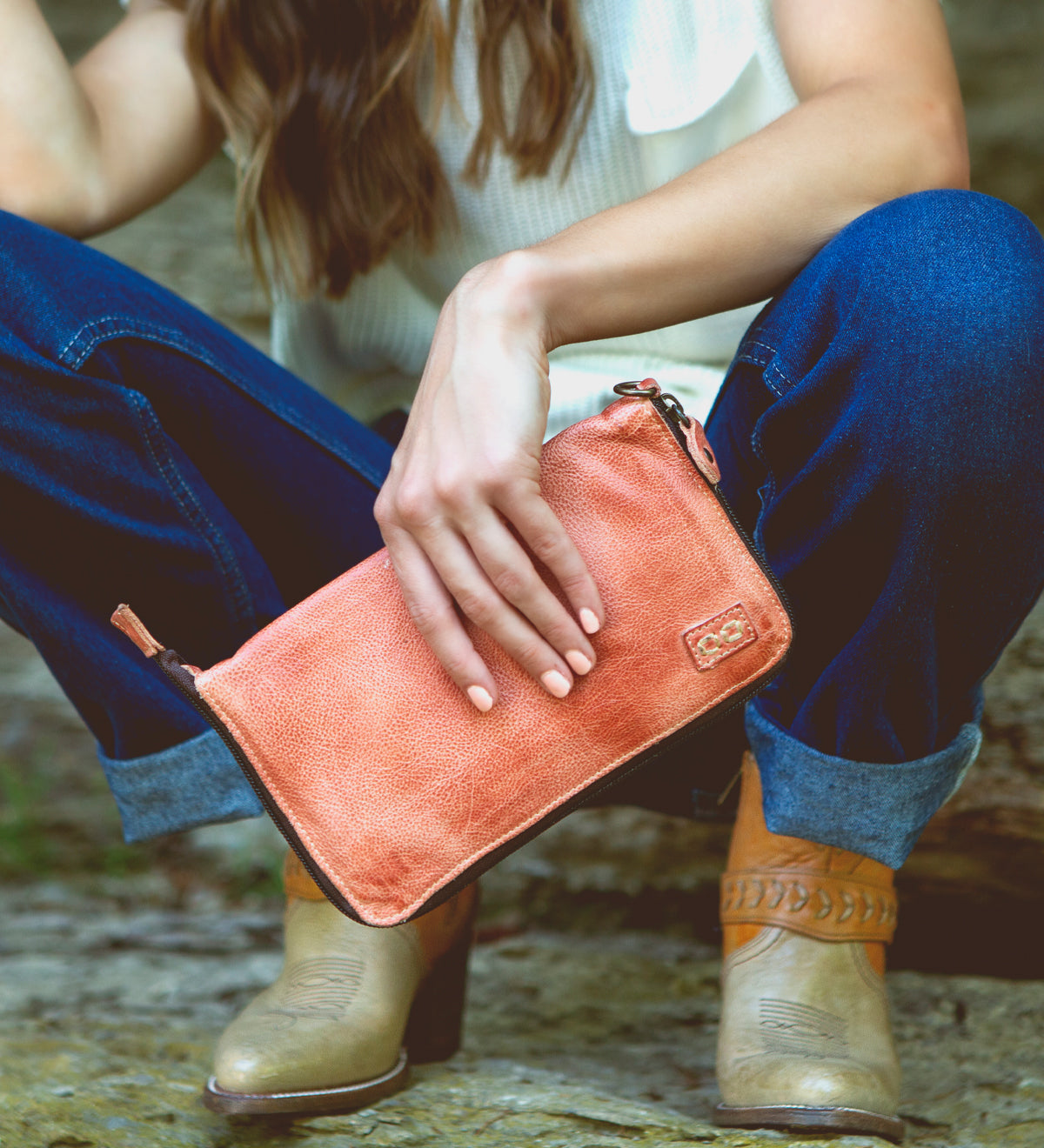 A woman holding a Bed Stu Templeton II pink leather clutch.
