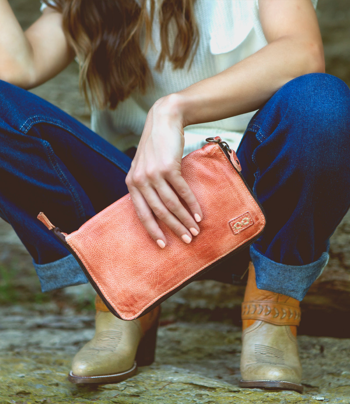 A woman holding a Bed Stu Templeton II pink leather clutch.