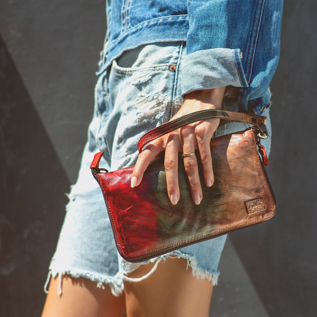 A woman holding a Bed Stu Templeton II colorful leather clutch.