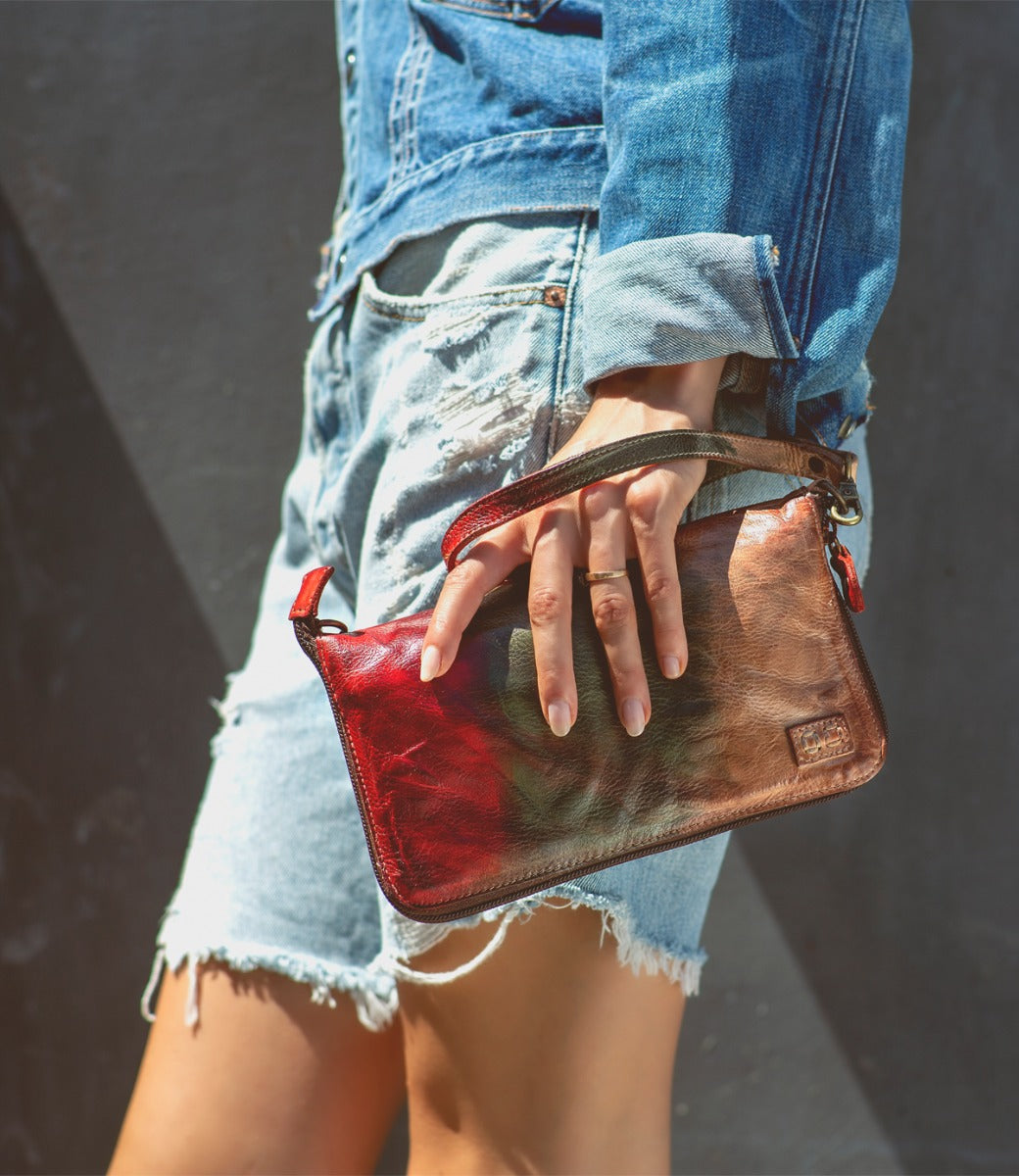 A woman holding a Bed Stu Templeton II colorful leather clutch.