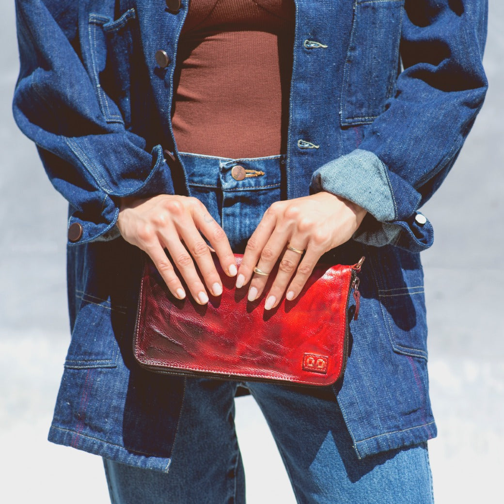 A woman holding a Bed Stu Templeton II red leather clutch.