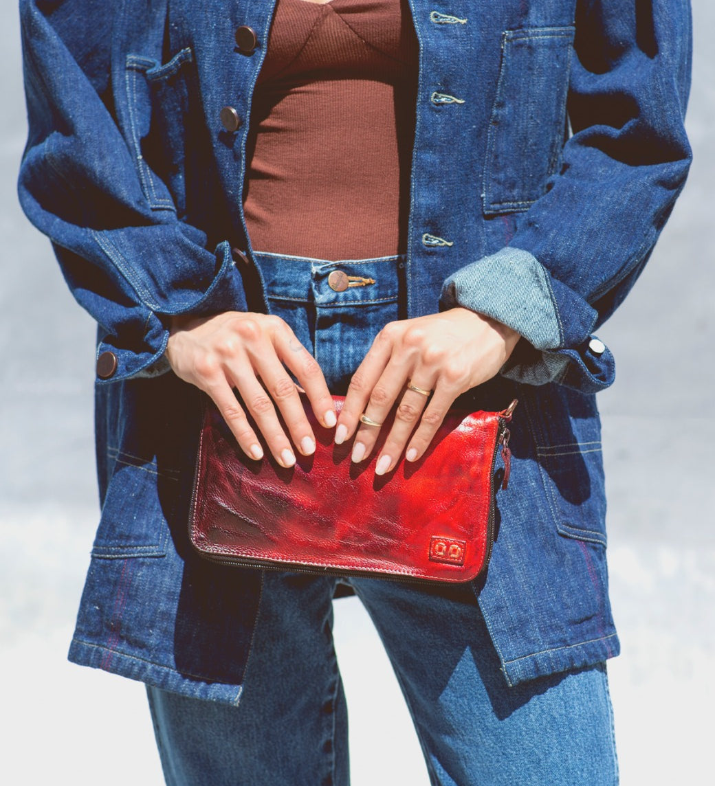 A woman holding a Bed Stu Templeton II red leather clutch.