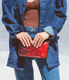 A woman holding a Bed Stu Templeton II red leather clutch.