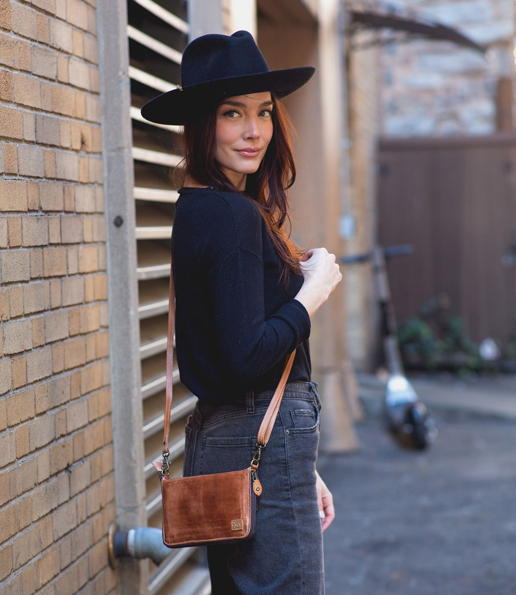 A woman wearing a Bed Stu Templeton II tan leather clutch.