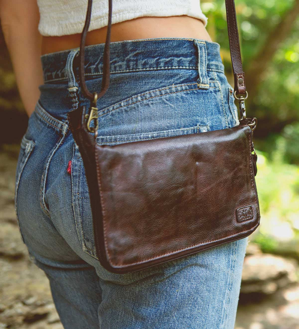 A woman wearing a Bed Stu Templeton II teak leather clutch.