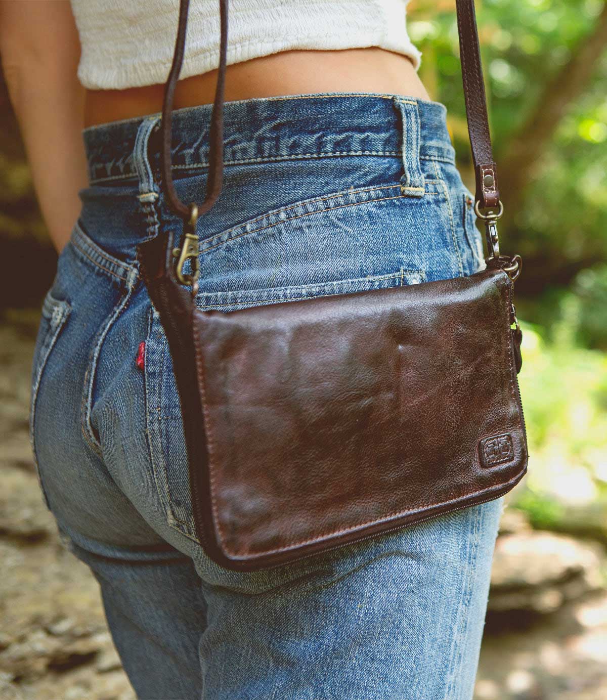 A woman wearing a Bed Stu Templeton II teak leather clutch.