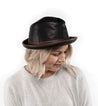 A woman wearing a black and brown Bed Stu fedora hat.