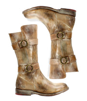 A pair of worn, light-brown Bed Stu "Turn" leather boots with buckles and straps, crafted from vegetable-tanned leather. The Goodyear welted construction ensures durability, despite the soles showing signs of wear and visible scuff marks.