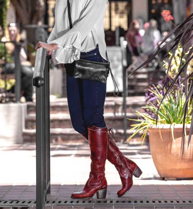 A woman wearing a Bed Stu Cadence black leather clutch.