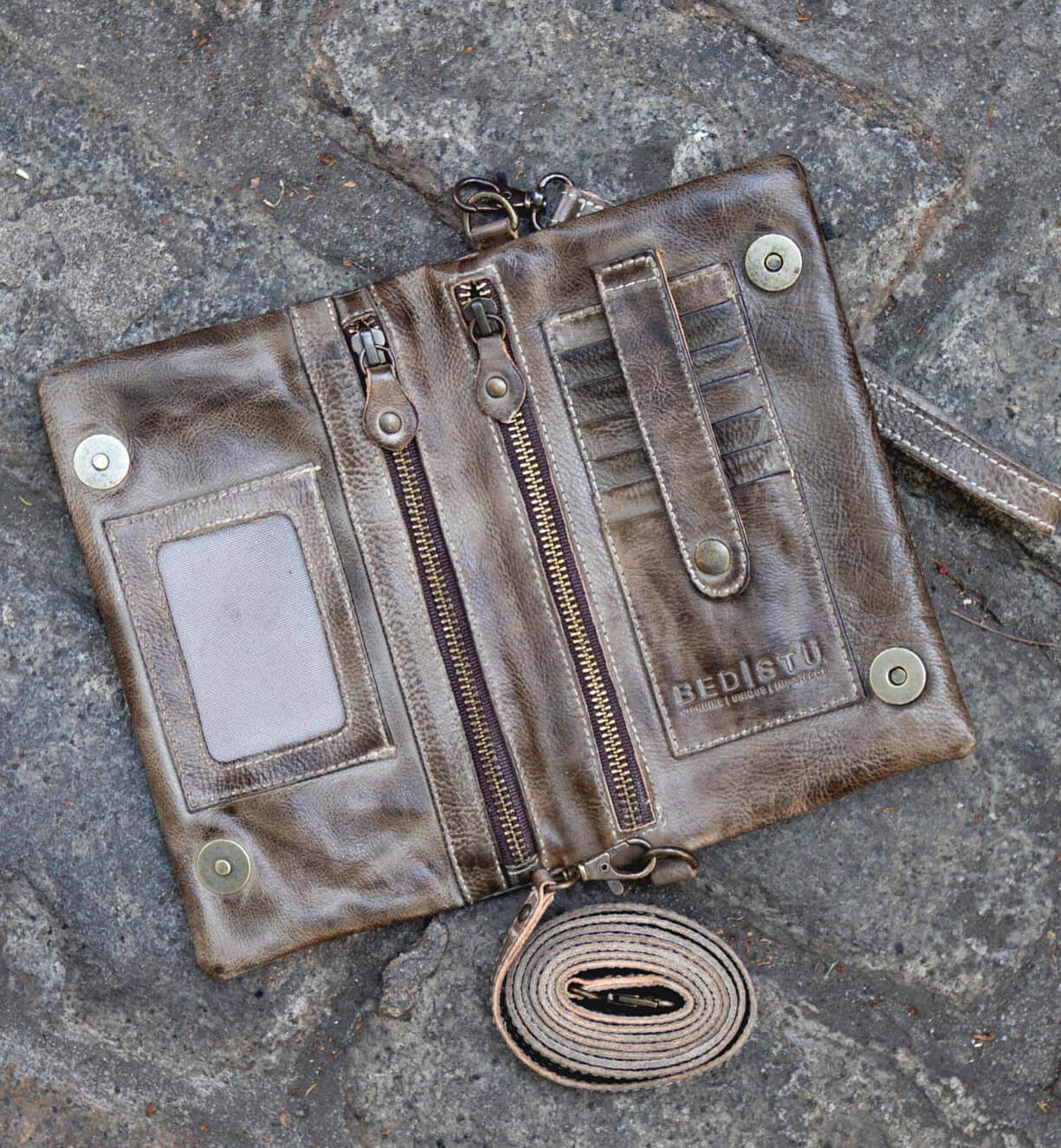 A brown leather Cadence wallet by Bed Stu laying on the ground.