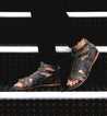 A person wearing a pair of black Bed Stu Claire sandals on stairs.