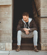 A man sitting on the steps of a Bed Stu building.