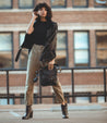 Woman posing in urban setting with a Bed Stu Isla leather jacket, casual attire, and Bed Stu Isla leather heeled booties featuring a vintage buckle accent.