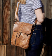 A woman wearing a striped shirt and a Bed Stu tan leather bag, the Jack